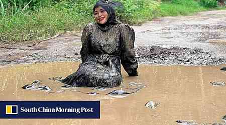 Indonesian mother who fell off motorbike sits in muddy pothole-filled roads to protest official inaction