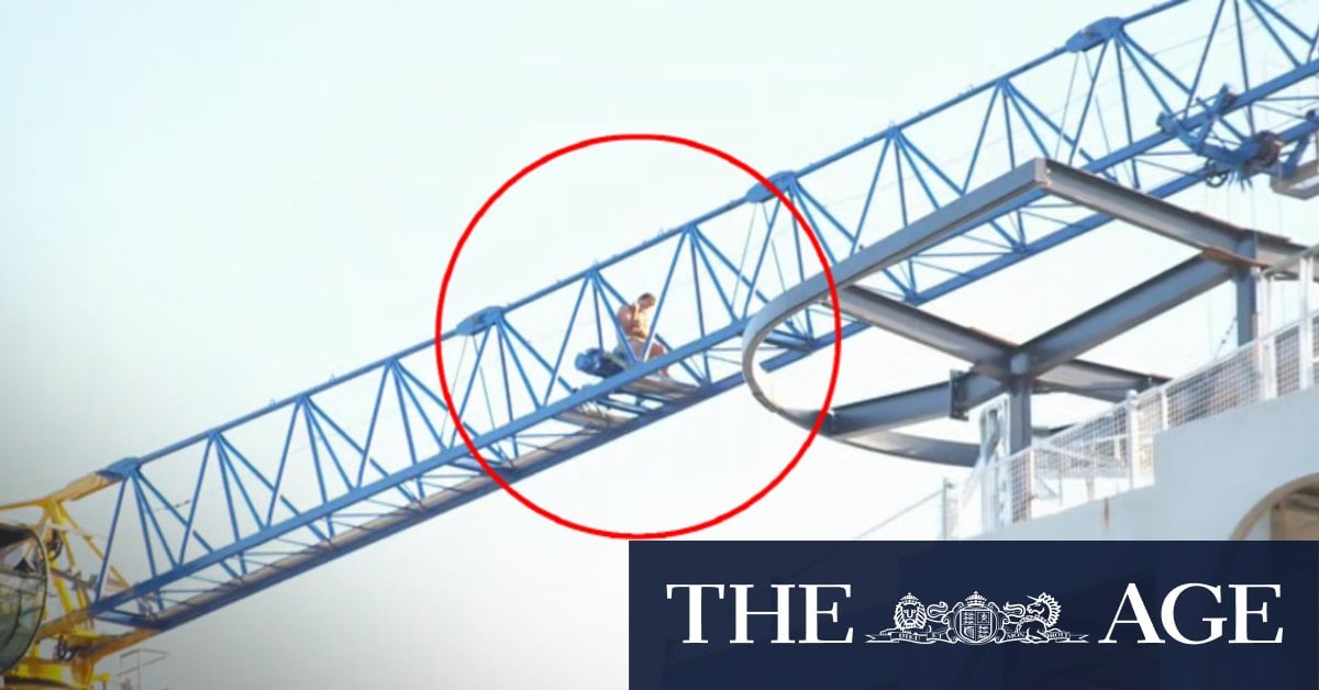 Man scales crane at construction site in Melbourne