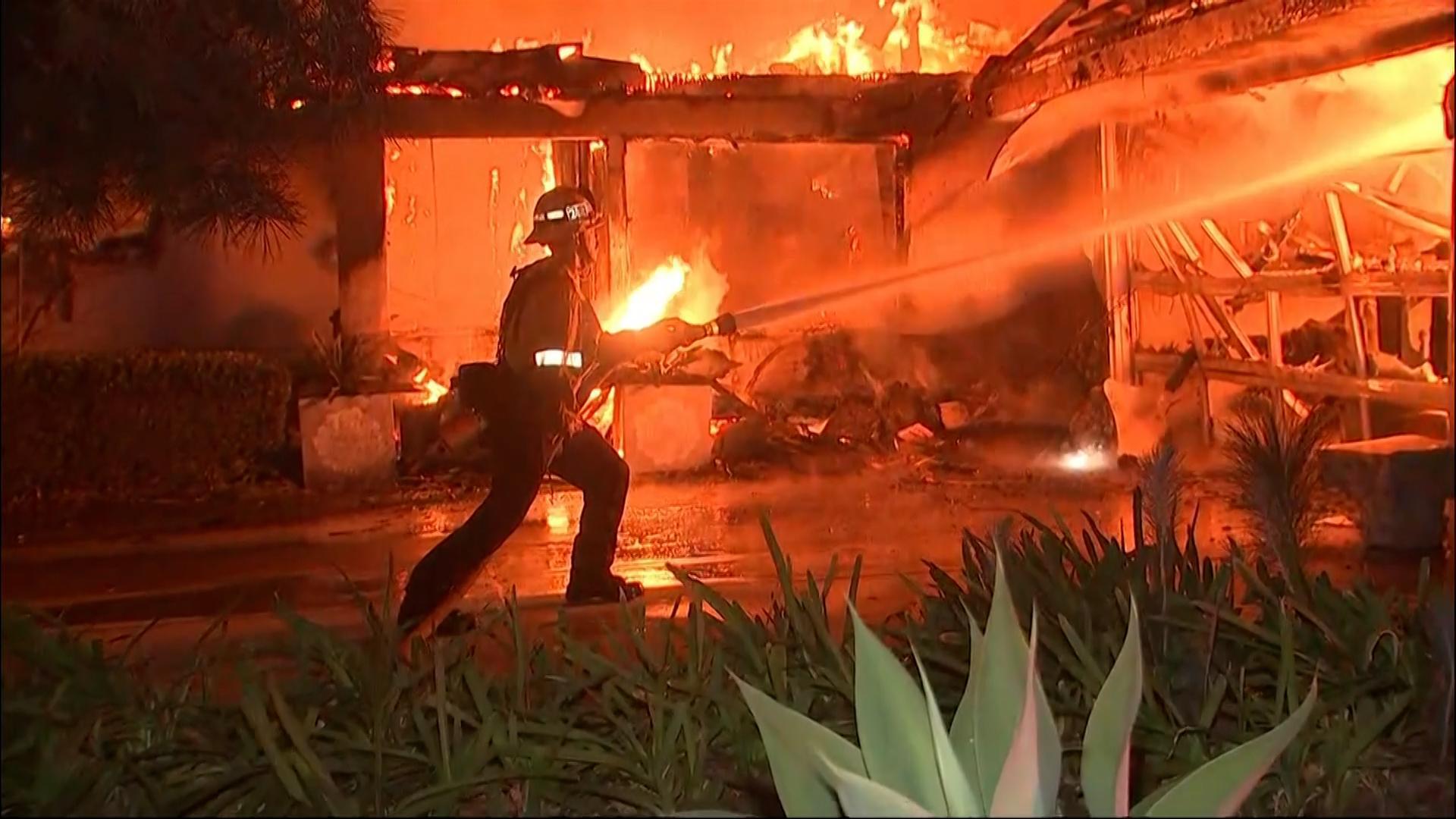 Thousands flee as wildfires burn out of control in and around Los Angeles and homes are destroyed